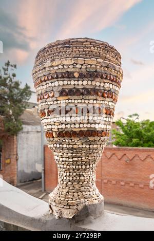Unica scultura a forma di vaso realizzata con una varietà di piccole pietre colorate e pezzi di vetro, presso la Bottle House di Ganja, Azerbaigian Foto Stock