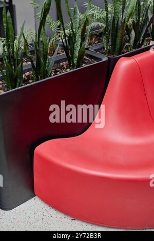 Immagine verticale dell'area comune nel centro affari con vegetazione e posti a sedere di design in rosso vivace, spazio fotocopie Foto Stock