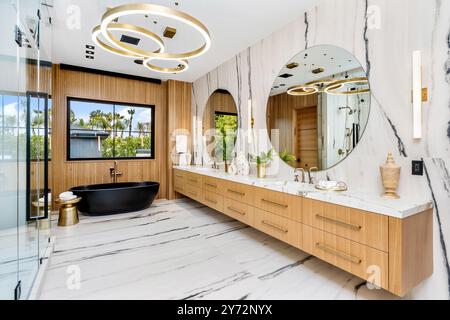 Un bagno moderno di lusso con vasca nera ed elegante pavimento in marmo. Foto Stock