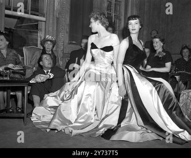 Il principale designer di abiti d'America, il 43enne Charles James, qui in visita aerea, ha accettato un invito del designer inglese Hardy Amies a dare una mostra di alcune delle sue mode a Londra. Per farlo ha preso in prestito alcuni degli abiti di celebrità che visitano questo paese . Spettacoli fotografici : alla sfilata di moda di Saville Row ieri sera, Hardy Aimes, seduta sul pavimento, guarda due manichini che indossano abiti delle collezioni di Charles James. 22 luglio 1949 Foto Stock