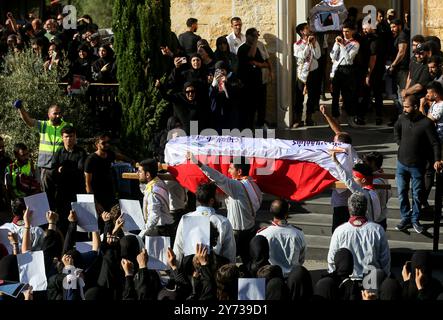 Maaysra, Libano. 27 settembre 2024. I sostenitori pro-iraniani di Hezbollah alzano i pugni e cantano slogan mentre portano una bara durante la processione funebre per 16 persone, tra cui tre militanti di Hezbollah, uccisi nell'attacco nel villaggio di Maaysra, a nord di Beirut. Crediti: Marwan Naamani/dpa/Alamy Live News Foto Stock