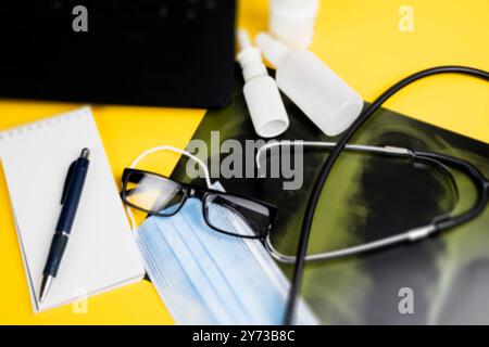 Su un tavolo giallo sono presenti uno stetoscopio, una maschera, un paio di occhiali, una penna e un notebook disposti in modo ordinato per un facile accesso e utilizzo Foto Stock