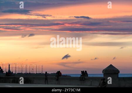 749 i cieli accesi al tramonto illuminano il crepuscolo sul parapetto delle scialle del Parque Maceo Park della Malecon Esplanade. L'Avana-Cuba. Foto Stock