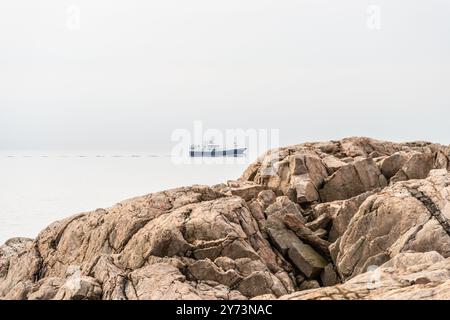 Lindesnes, Norvegia - 16 aprile 2022: Peschereccio da traino pelagico HG 264 Ruth lungo quasi 90 metri che passa Lindesnes Fyr in mare calmo. Foto Stock