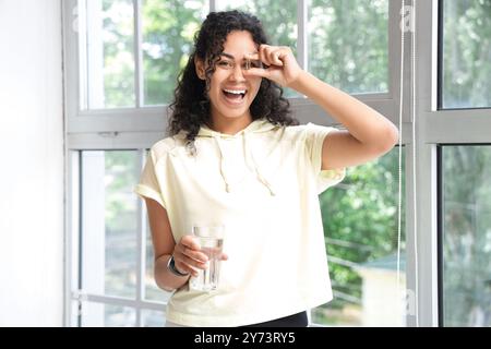 Giovane donna afroamericana che prende l'olio di pesce a casa Foto Stock