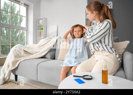 Madre che controlla la testa di sua figlia con la pediculosi a casa Foto Stock