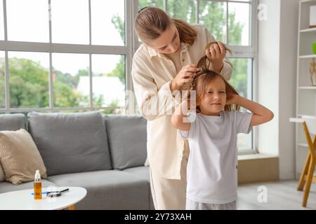 Madre che controlla i capelli di sua figlia con la pediculosi a casa Foto Stock