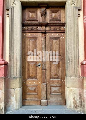 La fotografia cattura una vista dettagliata di un antico cancello medievale in legno e metallo, situato nelle strade di una storica città europea. Foto Stock