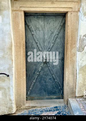 La fotografia cattura una vista dettagliata di un antico cancello medievale in legno e metallo, situato nelle strade di una storica città europea. Foto Stock