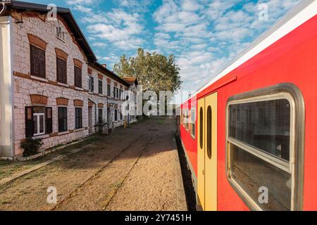 Pittoresca stazione ferroviaria di Podgorje sulla linea ferroviaria istriana. Magnifico edificio in pietra visto da un treno passeggeri rosso Foto Stock