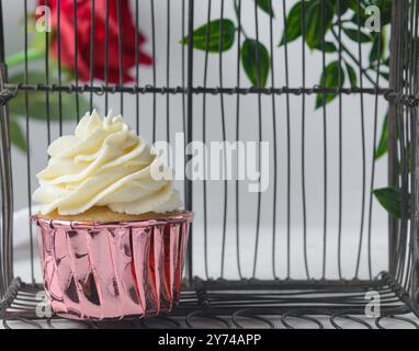 Cupcake rosa con alta vortice di crema di burro, cupcake in fodera di lamina rosa con crema alla vaniglia, cupcake smerigliati su sfondo bianco Foto Stock