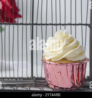 Cupcake rosa con alta vortice di crema di burro, cupcake in fodera di lamina rosa con crema alla vaniglia, cupcake smerigliati su sfondo bianco Foto Stock