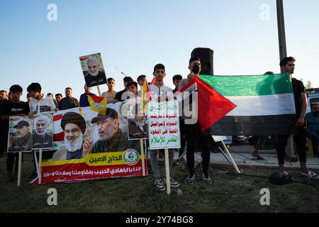 I sostenitori della fazione armata Kataeb Sayyid al-Shuhada (membro delle forze di mobilitazione popolare o PMF) detengono una bandiera palestinese (R) e uno striscione (L) includono ritratti del leader supremo iraniano Ayatollah Ali Khamenei (R), Abu Ala al-Walai, capo della Kataeb Sayyid al-Shuhada (2-R), Hezbollah di Mosul nella città di Mosul, Iraq. Foto Stock