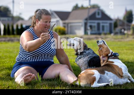 Una donna seduta su un prato con due cani. Foto Stock