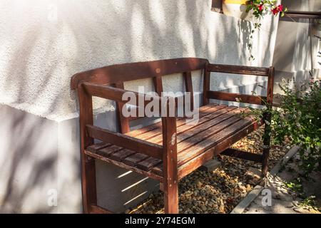 Panca di legno all'angolo della casa. Stagione estiva. Foto di alta qualità Foto Stock