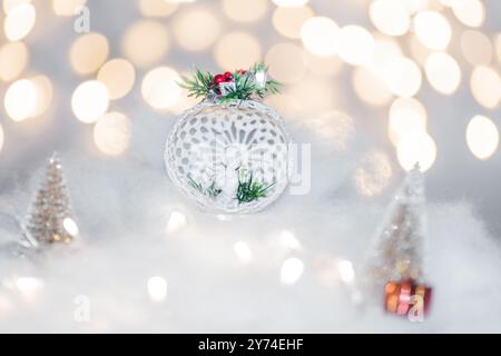 Concetto di deorazione natalizia durante le vacanze con un angelo di porcellana, neve bianca finta per un dicembre festivo. Sullo sfondo ci sono palline bokeh fatte di ligh Foto Stock