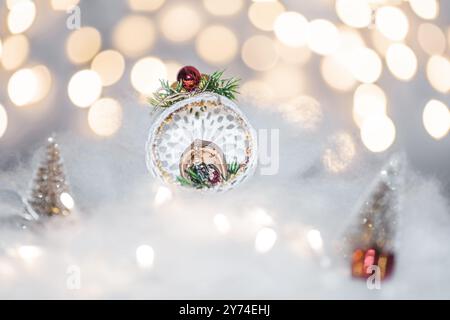 Concetto di deorazione natalizia durante le vacanze con neve finta bianca per un dicembre festivo. Sullo sfondo ci sono palline bokeh fatte di luci Foto Stock