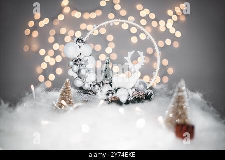 Concetto di deorazione natalizia durante le vacanze con un derr in porcellana, neve finta bianca per un dicembre festivo. Sullo sfondo ci sono palline bokeh fatte di luce Foto Stock