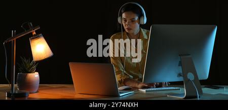 Programmatore con cuffie che lavora in ufficio di notte. Design banner Foto Stock