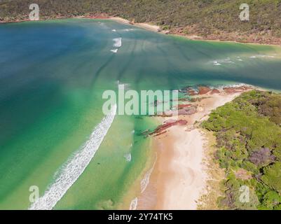 Vista aerea dell'oceano turchese intorno a un fiume che scorre oltre le spiagge sabbiose di Pambula Beach nel New Southern Wales, Australia. Foto Stock