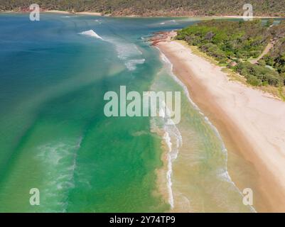 Vista aerea dell'oceano turchese intorno a un fiume che scorre oltre le spiagge sabbiose di Pambula Beach nel New Southern Wales, Australia. Foto Stock
