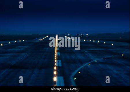 Immagine sfocata della pista dell'aeroporto illuminata al crepuscolo Foto Stock