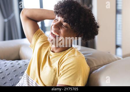 Ridendo e rilassandosi sul divano, giovane che si diverte con amici diversi, a casa Foto Stock