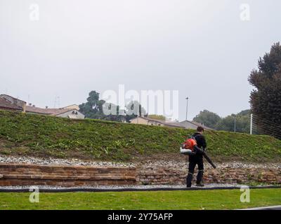 Cremona, Italia 26 settembre 2024 Un giardiniere si occupa di un parco in autunno, utilizzando un soffiatore di foglie per raccogliere le foglie cadute Foto Stock