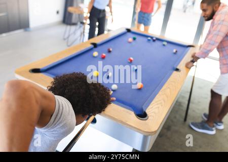 Giocare a biliardo, amici diversi che si divertono a giocare a biliardo in un ambiente informale, a casa Foto Stock