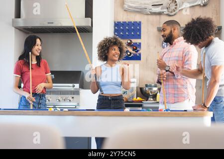 Piscina, gruppo di amici diversi che si divertono insieme e socializzano all'interno, a casa Foto Stock