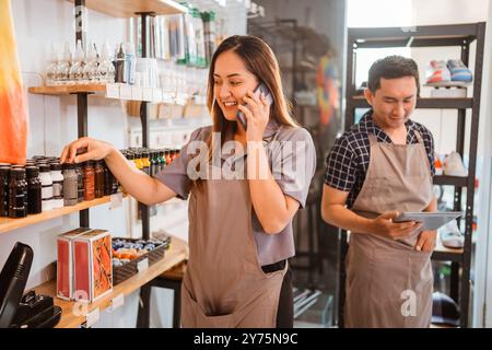 personale donna che riceve una telefonata mentre controlla il prodotto Foto Stock