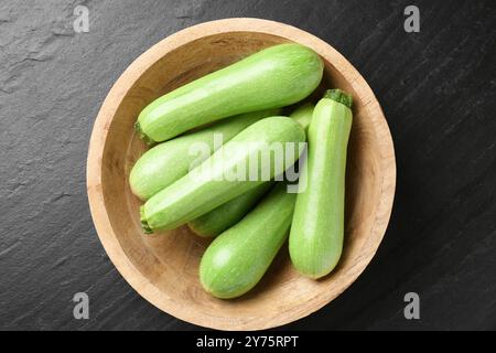 Zucchine fresche nella ciotola su un tavolo con superficie scura, vista dall'alto Foto Stock