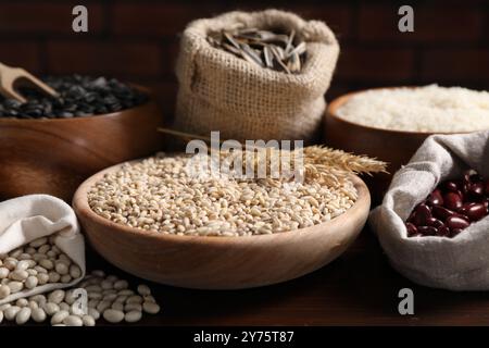 Diversi tipi di cereali, semi e legumi su tavola di legno Foto Stock