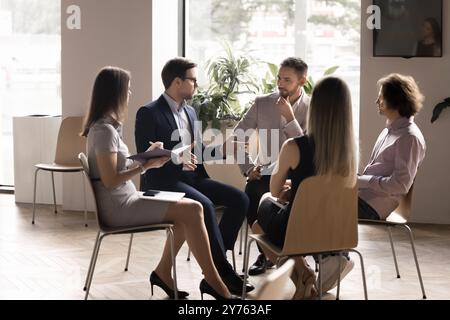 Capo serio che istruisce il team di dipendenti seduti in cerchio Foto Stock