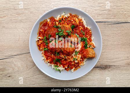 Polpette in salsa di pomodoro con spirali di pasta appoggiate su un piatto sul tavolo. Foto Stock