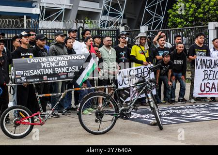 Bandung, Giava Occidentale, Indonesia. 28 settembre 2024. Un tifoso di Arema Malang MIFTAHUDDIN RAMLY insieme ai tifosi e ai residenti di Bandung scattano una foto accanto a una bicicletta con una bara sul retro che dice "giustizia per Kanjuruhan" a Bandung, Giava occidentale. Miftahuddin va in bicicletta da Malang dal 20 settembre 2024 a Giacarta, con una distanza di 800 chilometri, facendo campagna per la pace tra i tifosi in tutta l'Indonesia e chiedendo al contempo giustizia al governo e alle autorità legali per le vittime della tragedia dello stadio Kanjuruhan, che è passata per due anni Foto Stock