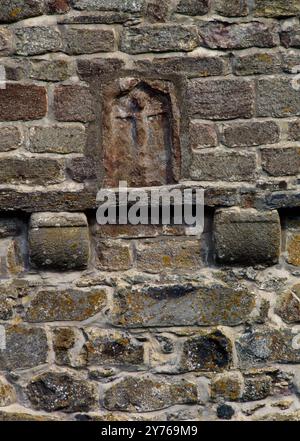 Dettaglio di una scena di crocifissione su un pannello situato nella parte anteriore ovest della chiesa medievale di Santa Maria, Caerhun, Conwy, Galles, Regno Unito, all'interno del forte romano di Canovium. Foto Stock