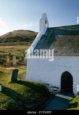 The S door & W end of Holy Cross C13th-14th Chapel, Mwnt, Cardigan, Wales, UK, guardando a nord-ovest verso Foel y Mwnt Headland. Costruito sulla cella di un santo primitivo Foto Stock