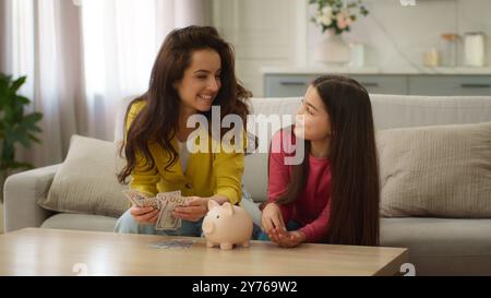 Famiglia felice donna caucasica donna contante dollari madre insegnamento risparmiare denaro bambino bambina figlia bambino che parla economia risparmio buttare giù Foto Stock