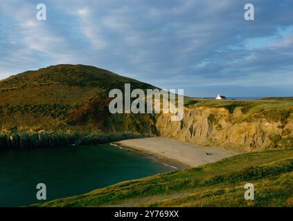 Vista a nord-est di Mwnt Bay, Foel y Mwnt Headland e Holy Cross C13th-14th Chapel, Cardigan, Galles, Regno Unito, con le persone che fanno un picnic sulla spiaggia. Foto Stock