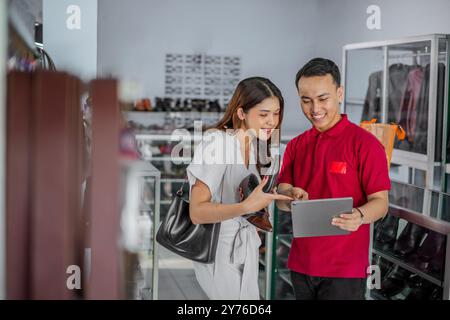 cliente donna e personale maschile che si rivolgono al tablet Foto Stock