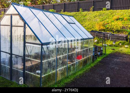 Serra di vetro nel giardino sul retro circondata da vegetazione autunnale, preparata per la prossima stagione invernale. Svezia. Foto Stock