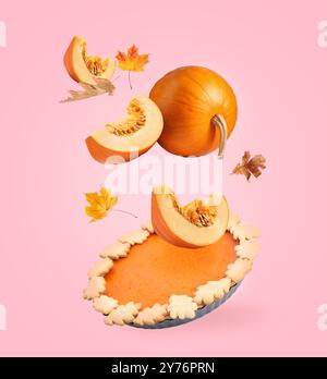 Torta autunnale, zucche e foglie d'arancia in aria su sfondo rosa Foto Stock