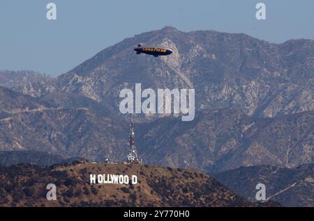 L'iconico Goodyear Blimp, simbolo dell'aviazione dirigibile, vola agevolmente sopra un aeroporto. Catturato contro un cielo limpido con vista degli hangar sottostanti Foto Stock