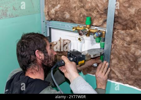 Un idraulico esperto unisce il tubo in polipropilene alla saldatrice in bagno durante l'installazione di nuovi impianti idraulici. Lavori di ristrutturazione di appartamenti per costruttori o r Foto Stock