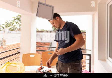 Installazione di una plafoniera a LED. Le mani di un elettricista stanno installando e collegando una lampada a soffitto. Restauro in spazi chiusi. Foto Stock