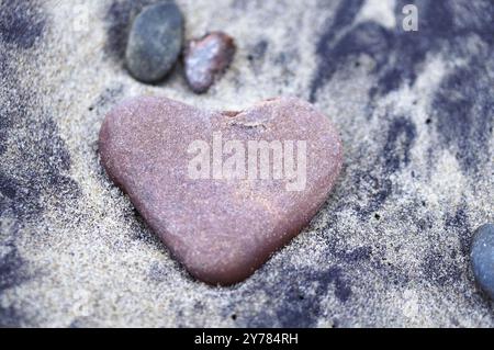 Cuore di pietra rossa, pietra marina a forma di cuore sulla sabbia Foto Stock
