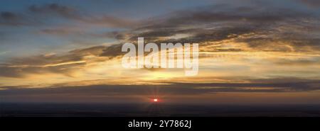 Panorama dell'alba con raggi rossi da dietro le nuvole. Cielo sfocato e nuvole astratte arancioni Foto Stock