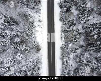 Vista aerea del drone della strada in idilliaco paesaggio invernale. Strada che corre attraverso la natura da una vista ad occhio di uccelli Foto Stock