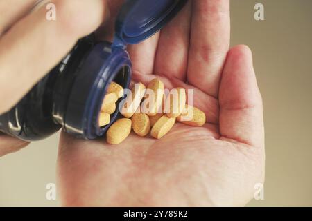 Un uomo che prende le compresse del complesso di vitamina B da un flacone. Primo piano. Foto Stock